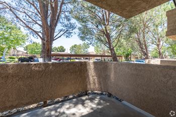 a balcony with a view of trees and a parking lot